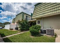 Inviting condo building with lush landscaping and unique architectural details, tile roof, and building signage at 1799 N Highland Ave # 106, Clearwater, FL 33755