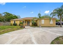 Beautiful tan home featuring a concrete circular driveway and well-maintained landscaping under a blue sky at 534 Berkley Ave, Tarpon Springs, FL 34689