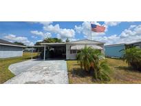 Charming single-story home featuring a carport, mature landscaping, and an American flag waving proudly at 5647 Arrowhead Dr, Zephyrhills, FL 33542