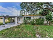Charming single-story home with a covered carport and a well-maintained front yard with mature trees at 629 Lexington St, Dunedin, FL 34698