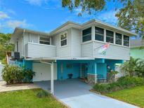 Charming elevated two-story home with carport and lush landscaping under a bright blue sky at 854 77Th N Ave, St Petersburg, FL 33702