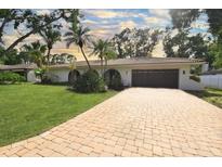 Charming home with a paver driveway, attached garage, and lush tropical landscaping at 8740 15Th N St, St Petersburg, FL 33702