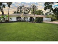Charming single-story home with a lush green lawn and mature tropical landscaping at 8740 15Th N St, St Petersburg, FL 33702