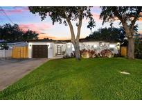 Charming home featuring a well-manicured lawn, stylish lighting, and a welcoming front entrance at 8848 Sunlit Cove Ne Dr, St Petersburg, FL 33702