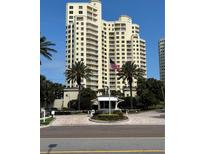 An exterior view of a high-rise condo building featuring balconies, a security gate and palm trees at 1200 Gulf Blvd # 404, Clearwater Beach, FL 33767