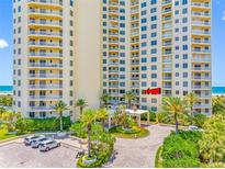 Stunning building exterior featuring lush landscaping and convenient covered entry with a circular drive at 1200 Gulf Blvd # 404, Clearwater Beach, FL 33767