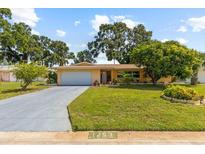 Charming single-story home featuring a well-manicured lawn, mature trees and a long driveway at 1453 62Nd S Ter, St Petersburg, FL 33705