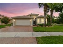 Inviting single Gathering home featuring a brick driveway, attached garage, and beautifully landscaped front yard at 16101 Cape Coral Dr, Wimauma, FL 33598