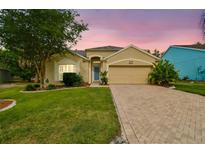 Charming single-story home featuring a paved driveway, a well-manicured lawn, and mature landscaping at 1758 Biarritz Cir, Tarpon Springs, FL 34689