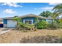 Charming blue home featuring a one car garage and a stone accent wall at 3621 Beacon Square Dr, Holiday, FL 34691