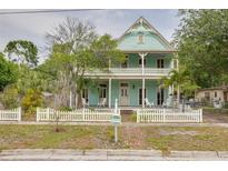 Charming two-story home with a wide porch, white picket fence, and lush green trees at 6904 S Fitzgerald St, Tampa, FL 33616