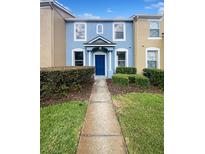 Charming two-story townhome featuring a blue facade, manicured landscaping, and inviting entryway at 1237 Blenhem Ct, Wesley Chapel, FL 33543