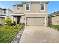 Charming two-story home featuring a two-car garage, and beautifully landscaped front yard at 17012 Oval Rum Dr, Wimauma, FL 33598