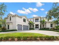 Elegant two-story home featuring a three-car garage, manicured lawn, and a grand entrance with lush tropical landscaping at 419 S Shore Crest Dr, Tampa, FL 33609