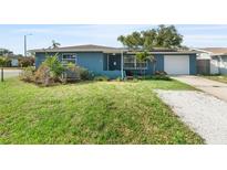 Charming blue home featuring a well-manicured lawn, mature plants, and a single-car garage at 4238 Glissade Dr, New Port Richey, FL 34652