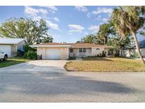 Charming single-story home featuring an attached garage, manicured lawn, and mature trees at 504 Casas Bonitas Dr, Nokomis, FL 34275