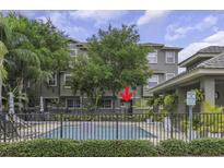 View of community pool in front of condo building with lush landscaping and a visitor's parking sign at 7130 102Nd Ln, Seminole, FL 33772