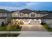 Elegant two-story home featuring a paved driveway and a welcoming front porch with cozy seating at 7819 Notched Pine Bnd, Wesley Chapel, FL 33545