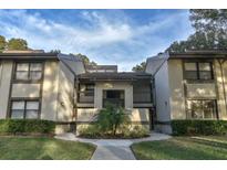 Low angle of a two-story condo with neutral siding, dark trim, and a small garden at the entrance at 124 Woodlake Wynde, Oldsmar, FL 34677