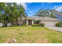 Charming single-story home featuring a well-manicured lawn, mature trees, and an attached two-car garage at 4311 W Beach Park Dr, Tampa, FL 33609