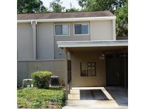 Townhouse exterior view with a covered carport area and neutral-toned siding, surrounded by greenery at 8011 Peach Dr # 103, Tampa, FL 33637