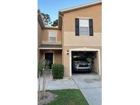 Two-story townhome with a one-car garage, dark shutters, and manicured landscaping at 8423 Edgewater Place Blvd, Tampa, FL 33615