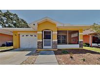 Charming single-story home featuring a yellow exterior, screened porch, attached garage, and well-maintained landscaping at 1850 Fuller Dr, Clearwater, FL 33755