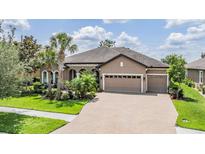 Beautiful single-story home featuring a three-car garage and lush landscaping at 32242 Summerglade Dr, Wesley Chapel, FL 33545