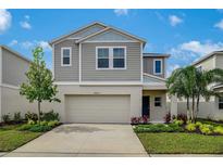Charming two-story home featuring a two-car garage, well-maintained lawn, and colorful landscaping under a beautiful sky at 37122 Sagemoor Dr, Zephyrhills, FL 33541