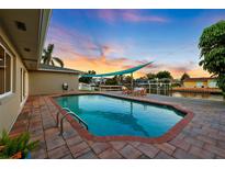 Beautiful waterfront home featuring a private pool, dock and patio with waterfront views at sunset at 3912 Doral Dr, Tampa, FL 33634