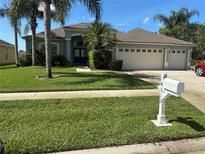 Charming single-story home featuring a three-car garage, well-maintained lawn, and tropical landscaping at 4512 River Overlook Dr, Valrico, FL 33596
