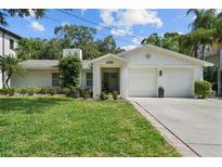 Charming single-story home with a lush front lawn, blooming flowers, and a two car garage at 4705 W Estrella St, Tampa, FL 33629