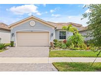Charming single-story home with a paver driveway, mature landscaping, and a beige two-car garage door at 4914 Sienna Isles Ave, Wimauma, FL 33598