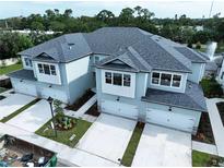 New townhomes featuring multiple garage doors, stone accents, and professionally landscaped grounds at 7798 93Rd N St # 1, Seminole, FL 33777