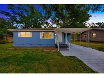 Charming blue home featuring a covered carport, well-maintained lawn, and a welcoming facade at 1304 N Ferrell St, Plant City, FL 33563