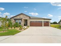 Charming single-story home with a stone facade, well-manicured lawn, and a two-car garage at 13098 Wellspring Dr, Lithia, FL 33547