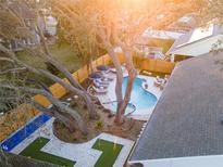 Aerial view of a backyard with a pool, lounge area, outdoor bowling alley, and putting green at 1394 Stonehenge Way, Palm Harbor, FL 34683