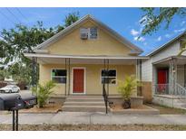 Charming yellow home with a welcoming front porch, complemented by fresh landscaping and a well-maintained yard at 2402 Harper St, Tampa, FL 33605