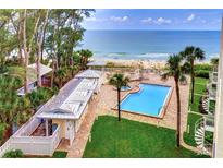 Aerial view of a pool near the beach, with sun loungers and palm trees, creating a relaxing tropical oasis at 2504 Gulf Blvd # 201, Indian Rocks Beach, FL 33785