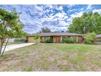 Charming single-story brick home with a well-maintained lawn and a yellow door and garage at 2524 Laurelwood Ln, Valrico, FL 33596