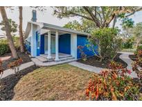 Charming blue home with a covered front porch and stone walkway, surrounded by lush landscaping at 330 Pineapple St, Tarpon Springs, FL 34689