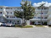 Bright white condo building featuring decorative railings, well-maintained landscaping, and ample parking at 8055 112Th St # 406, Seminole, FL 33772