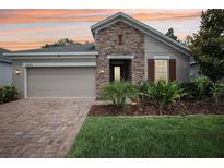 Charming single-story home with a stone facade, well-manicured lawn, and two-car garage at 10625 Cardera Dr, Riverview, FL 33578