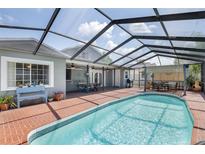 Relaxing screened-in pool area with brick pavers, dining area, and lush surroundings, perfect for outdoor entertaining at 12913 126Th Ter, Largo, FL 33774