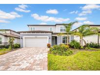 Charming two-story home featuring a paved driveway, lush landscaping, and an attached two-car garage at 13855 Sharp Hawk Dr, Riverview, FL 33569