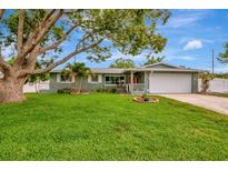 Charming single-story home featuring a lush green lawn, mature trees, and a two-car garage at 1398 Lemon St, Clearwater, FL 33756