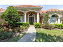 Charming home featuring a tile roof, arched entryway, and lush landscaping at 16124 Suncrest Shores Dr, Odessa, FL 33556