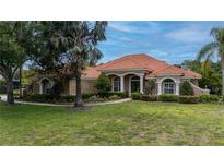 Charming, single-story home with a well-manicured lawn, lush landscaping, and a clay tile roof at 16124 Suncrest Shores Dr, Odessa, FL 33556