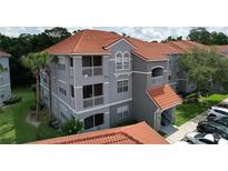 Gray condo building with orange tile roof, white balcony railings, and well-maintained landscaping at 18001 Richmond Place Dr # 330, Tampa, FL 33647