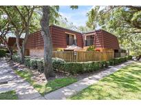 Charming townhouse featuring a private fenced patio and red-tiled roof, surrounded by lush landscaping and mature trees at 2626 2Nd Ct, Palm Harbor, FL 34684